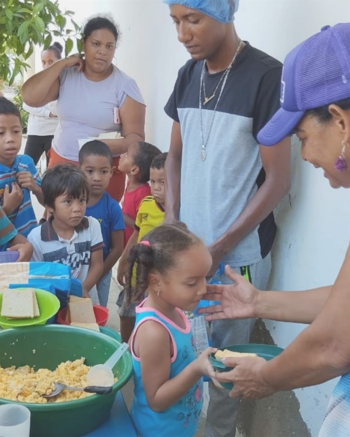 Jóvenes voluntarios sirviendo alimentos a niñas y niños de la comunidad